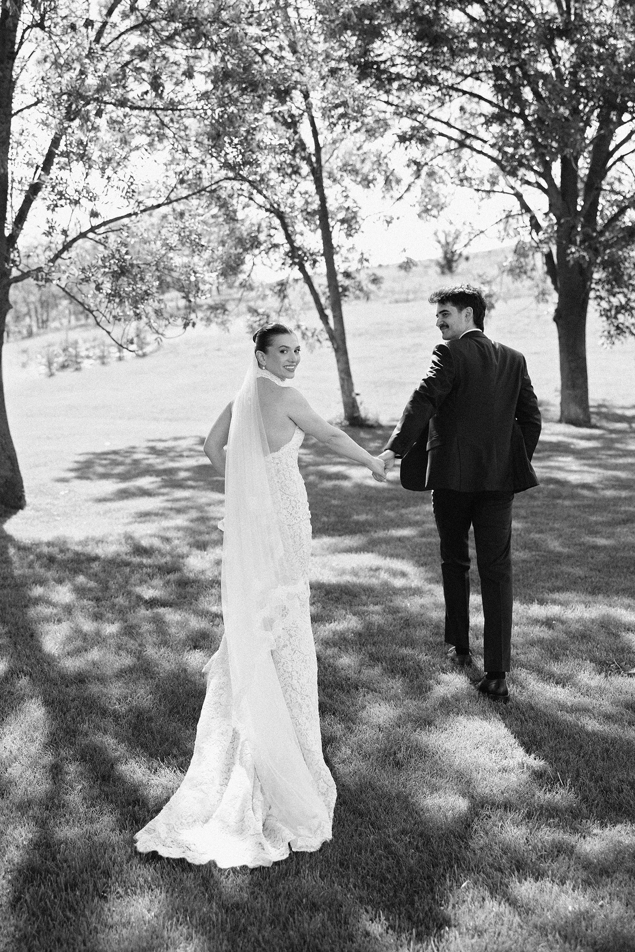 Wedding couple walking beneath trees
